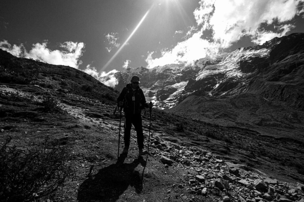 Randonneur avec des bâtons de randonnée sur un sentier rocheux en montagne