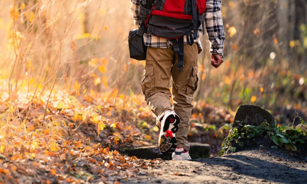 Randonneur en pantalon de randonnée sur un sentier forestier en automne