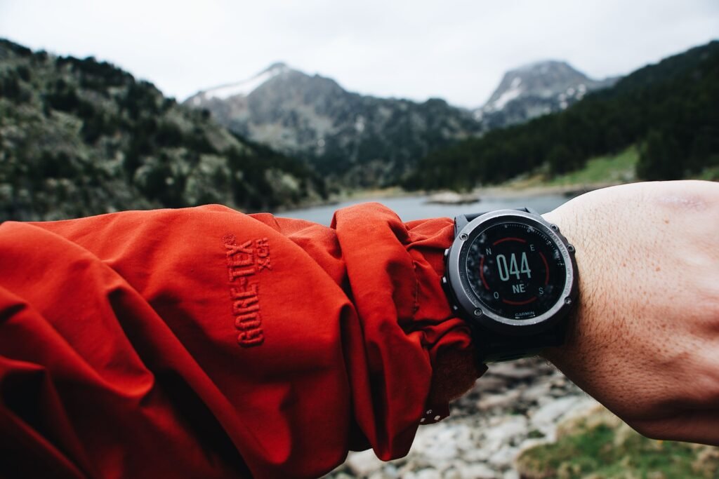 Randonneur consultant une montre GPS devant un paysage de montagne