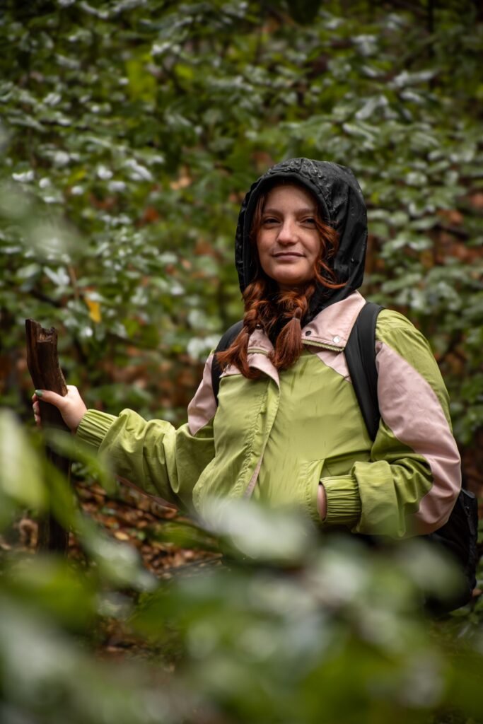 Randonneuse en imperméable dans une forêt humide sous la pluie