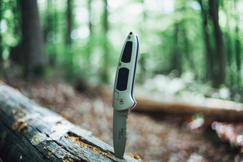 Couteau pliant posé sur un tronc en forêt pour une randonnée