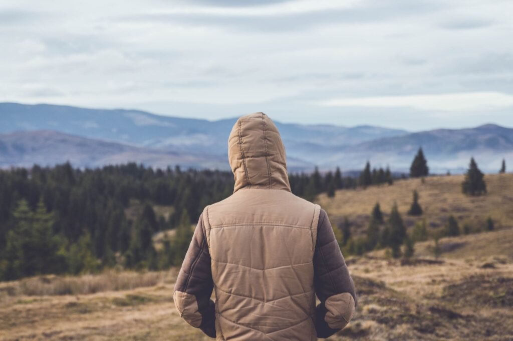 Randonneur en veste face à des montagnes et une forêt en automne